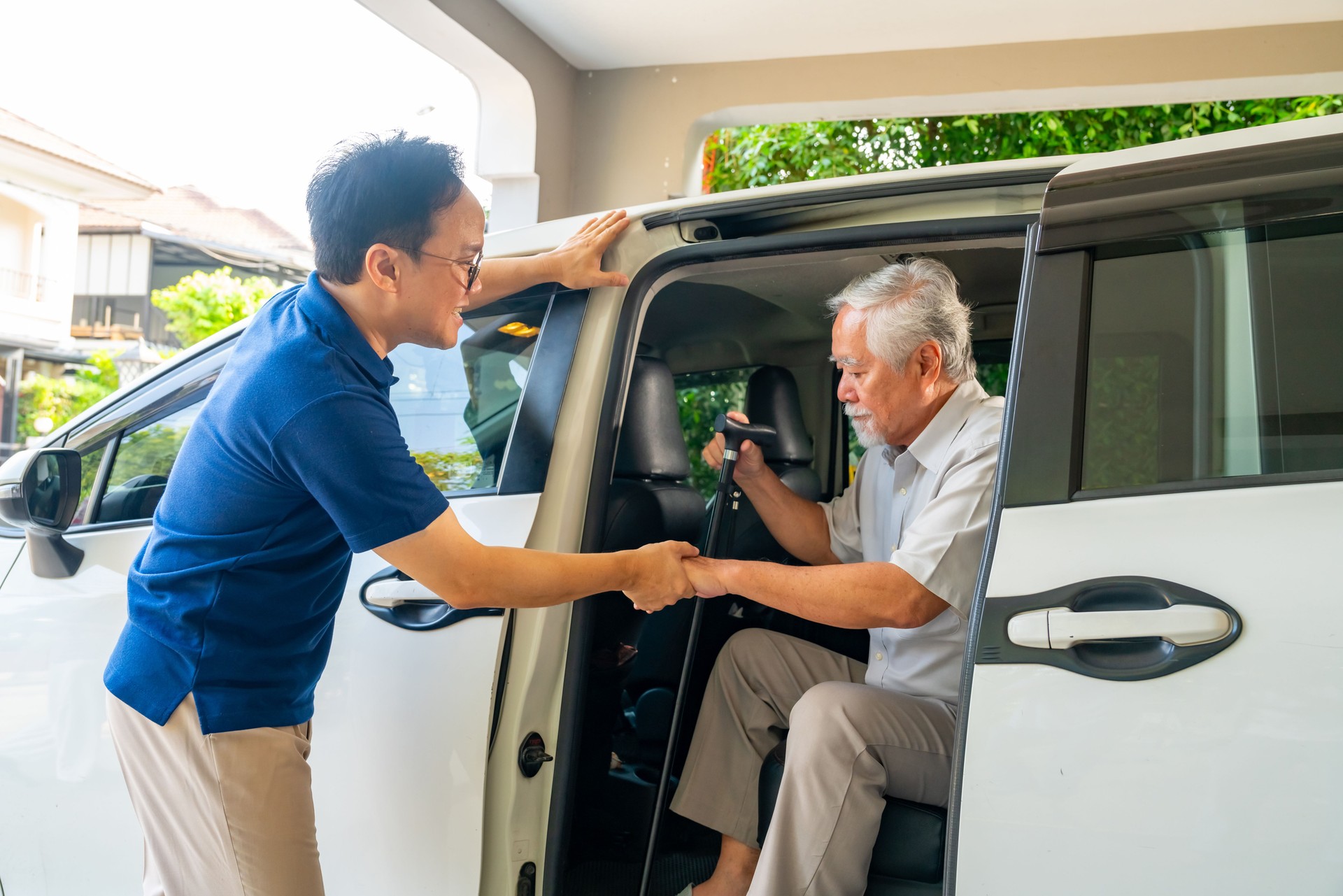 Caregiver helping senior man get in the car.