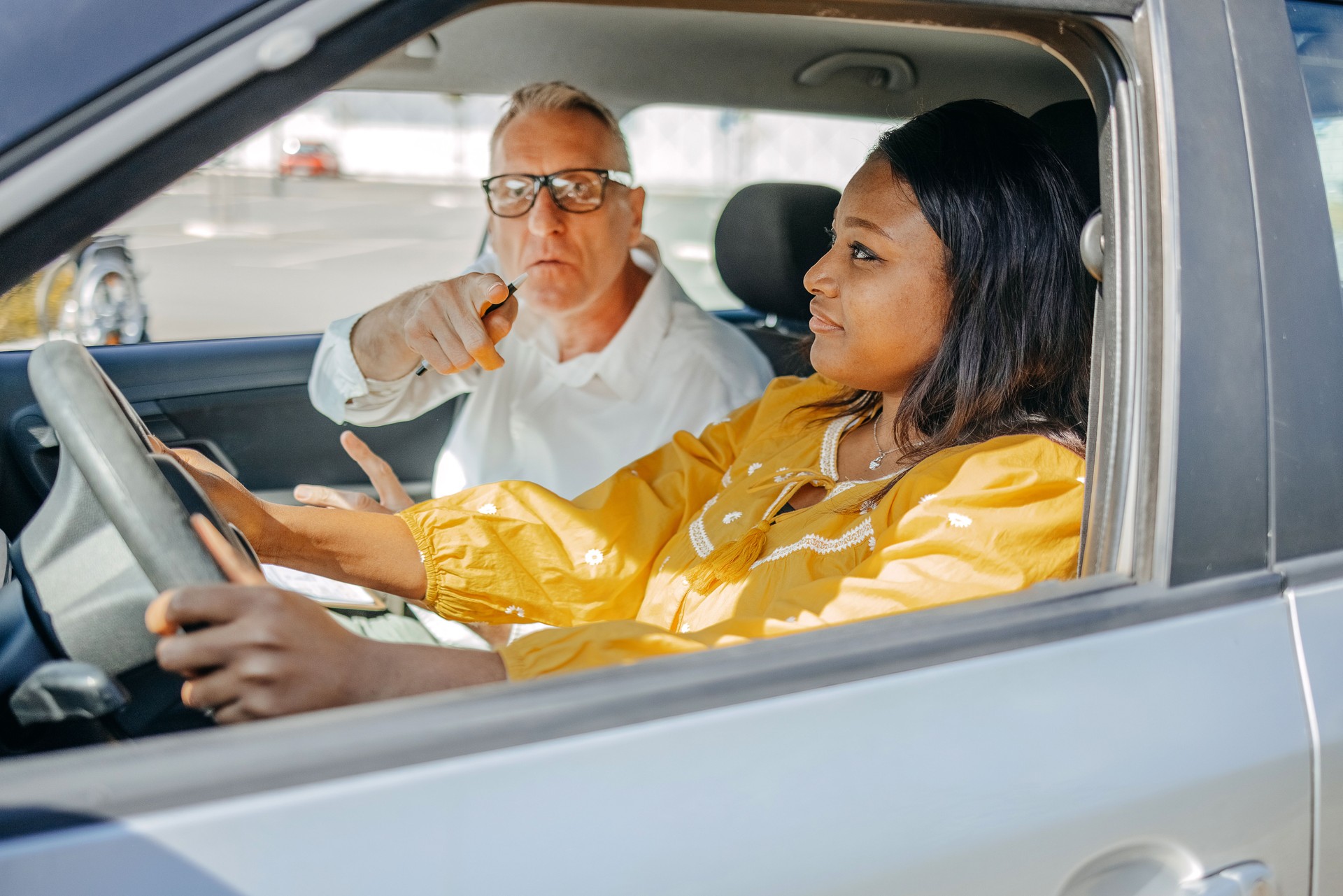 Young woman taking driving lessons with her instructor